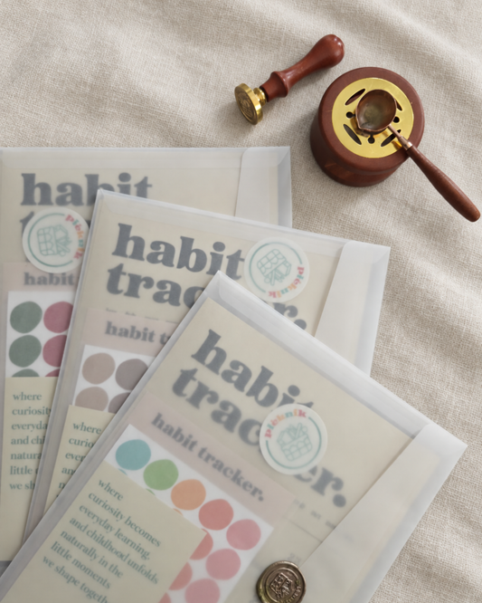 Habit tracker sheets and envelopes displayed on beige linen with a wooden wax seal stamp