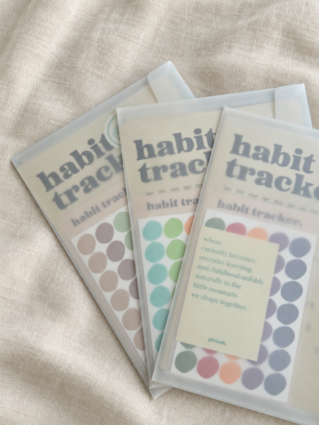 Three Premium Habit Tracker sets with different sticker color options displayed on linen
